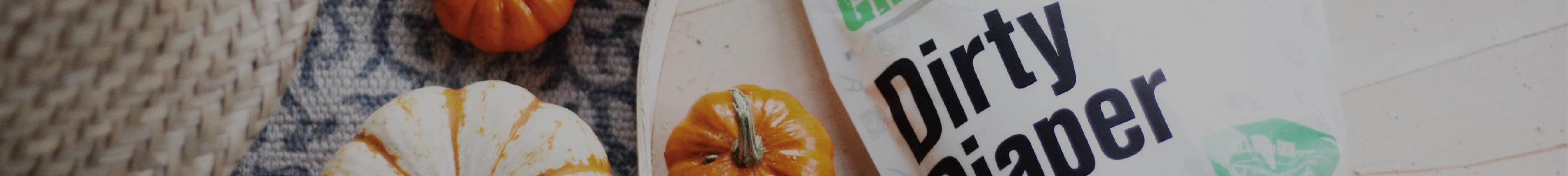 Three small pumpkins next to a pouch labeled dirty dinger on a textured surface.