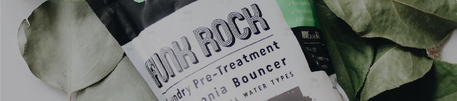 A package labeled Punk Rock Laundry Pre-Treatment placed on green leaves.