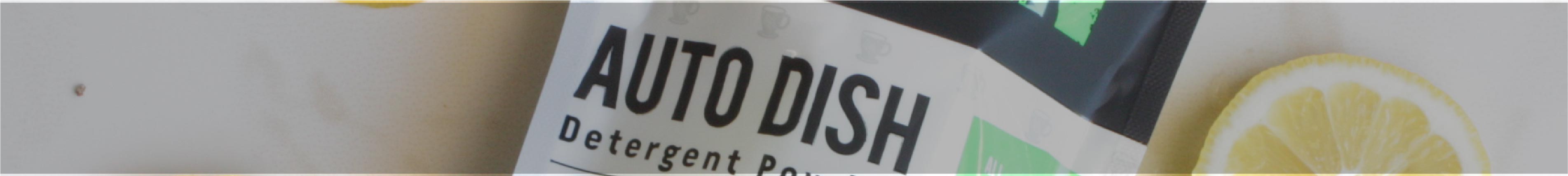 A partial bag labeled AUTO DISH Detergent next to a lemon slice on a light surface.