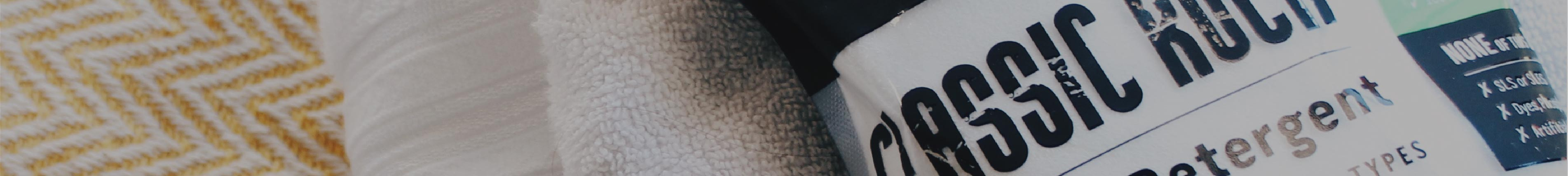 Close-up of laundry detergent bottle next to white and yellow striped towels.