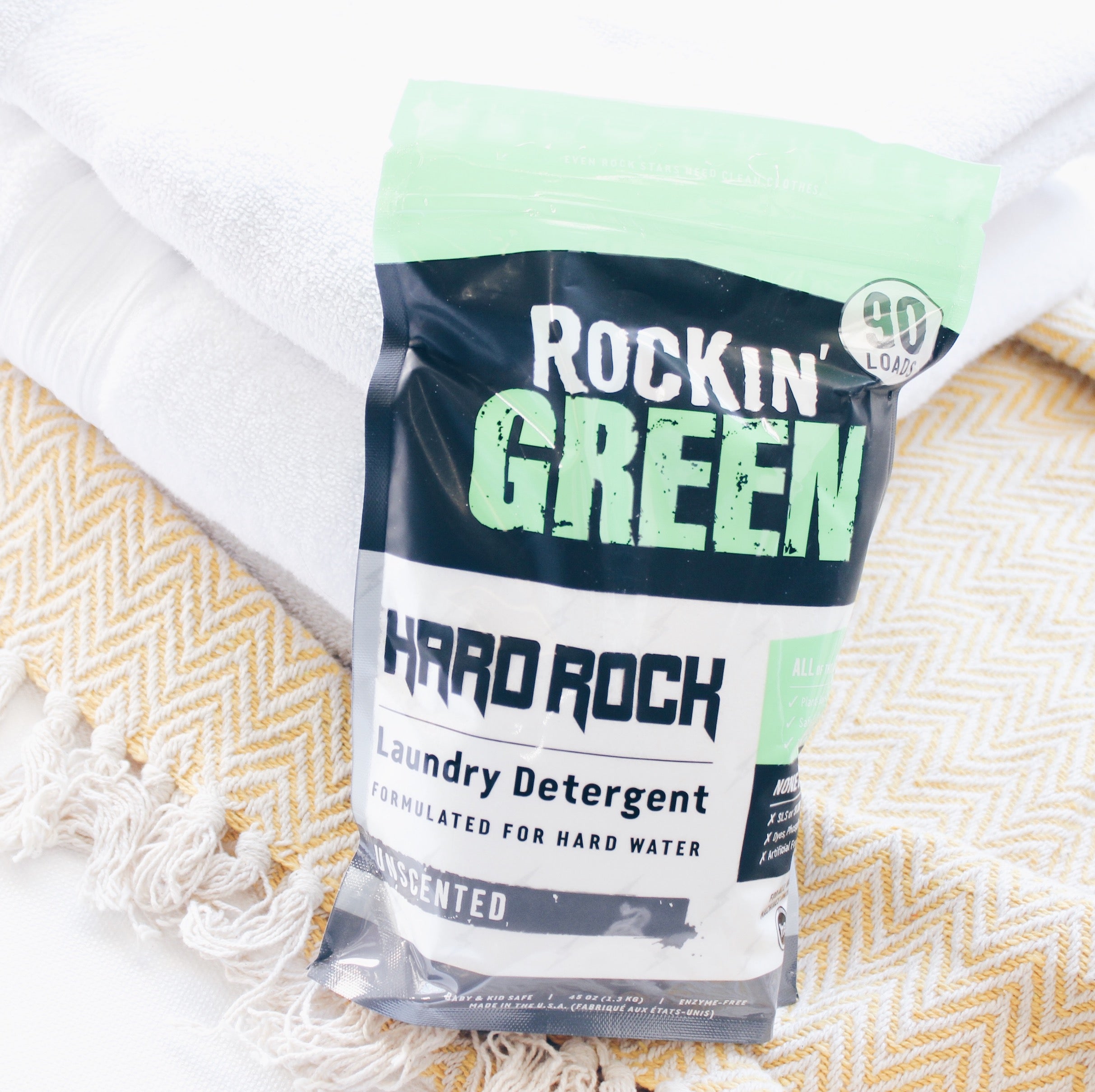 Rockin Greens Hard Rock Laundry Detergent - Unscented, on a pile of towels.